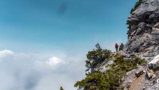 Wandelaars op het smalle Fürstensteig-pad in Liechtenstein met uitzicht op de wolken onder het pad