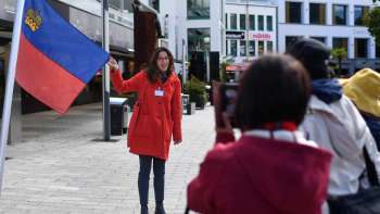Stadsgids met Liechtensteinse vlag verwelkomt groep toeristen in Vaduz