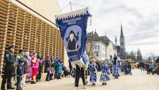 Feestelijk geklede Törmleguger Vaduz bij de carnavalsoptocht in Vaduz, Liechtenstein, voor het regeringsgebouw en de kathedraal.