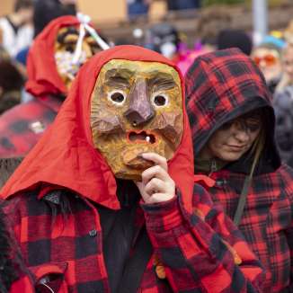 Deelnemers met bewerkte houten maskers en rode en zwarte kostuums tijdens de carnavalsoptocht in Malbun