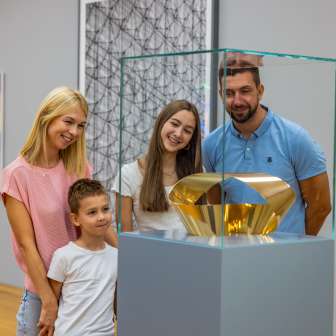 Familie kijkt naar een gouden sculptuur in het Kunstmuseum Liechtenstein - kunst voor jong en oud in het hart van Vaduz.