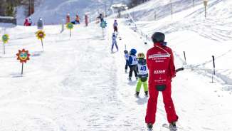 Skileraar begeleidt kinderen op de oefenlift in Malbun - ideaal skigebied voor gezinnen en beginners in Liechtenstein.
