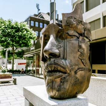 Moderne bronzen sculptuur van een gezicht in de voetgangerszone van Vaduz.