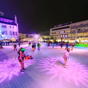 Mensen schaatsen 's avonds op de verlichte ijsbaan van Vaduz on Ice in het centrum van Vaduz