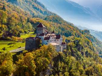 Kasteel Vaduz op een beboste heuvel in een herfstlandschap in Liechtenstein