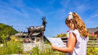 Meisje met kaart voor het gemsbeeld in Malbun - kindvriendelijke ontdekkingstocht in het familievakantieoord in Liechtenstein.