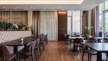 Modern restaurant Kommod met donkerhouten interieur en gestoffeerde banken