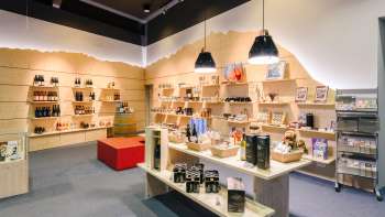  Helder bezoekerscentrum met moderne houten rekken vol souvenirs, specialiteiten en informatiemateriaal