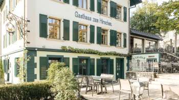 Uitnodigend terras met houten tafels en stoelen voor Gasthaus zum Hirschen