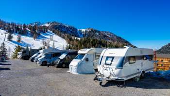 Verschillende campers staan geparkeerd op de zonnige kampeerplaats in Malbun met een bergpanorama op de achtergrond