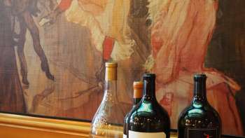 Drie flessen wijn voor een artistieke muurschildering in de Brasserie Burg - mediterrane elegantie ontmoet artistieke flair.