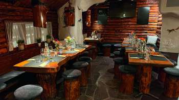Uitzicht op een rustiek restaurant met houten meubels, groen gedekte tafels en kaarsen