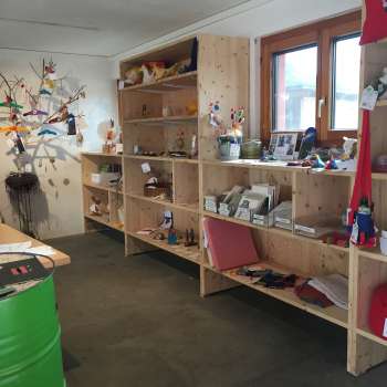 Interieur van de Birkahoflädile met houten schappen vol regionale producten, decoratief ontworpen met kleurrijke elementen - boerderijwinkel in Liechtenstein.