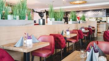 : Ruim gedekte tafels in het PUR Restaurant & Bar met rode stoelen en bloemendecoraties.