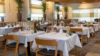 Uitzicht op het stijlvol ingerichte Alpspitz restaurant met witgeklede tafels en een moderne, lichte sfeer.