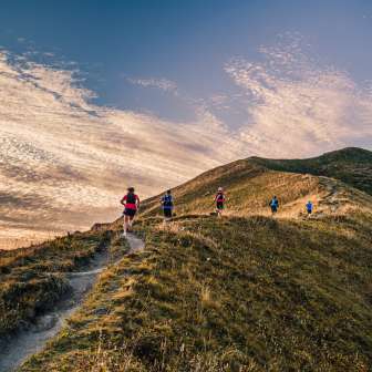 Groep trailrunners op een bergrug bij Malbun, Liechtenstein, in het avondlicht