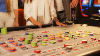 Gasten aan de speeltafel plaatsen hun fiches in het Casino Admiral Triesen, omgeven door een spannende casinosfeer.