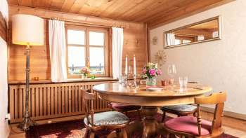 Gezellige eetkamer met houten lambrisering, ronde eettafel en rustiek interieur