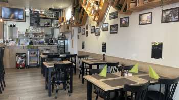 Gezellig restaurantinterieur met moderne houten tafels, groene servetten en decoratieve elementen