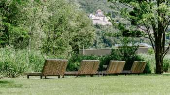 Rustige ligweide met houten ligstoelen in natuurpark Haberfeld, met uitzicht op het kasteel op de achtergrond.