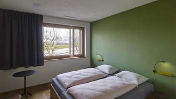 Tweepersoonskamer met een groen geschilderde muur in de jeugdherberg Schaan-Vaduz
