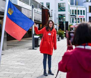 Stadsgids toont de Liechtensteinse vlag tijdens een rondleiding door het centrum van Vaduz