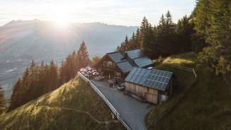 Panoramafoto van een afgelegen berghut in Liechtenstein met uitzicht op de Rijnvallei en zonnetechnologie op het dak
