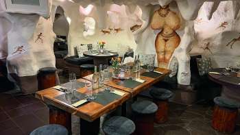 Close-up van een gezellig restaurant met houten tafels en stoelen, versierd met bloemen en kaarsen