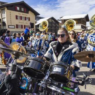 Guggenmusik in kleurrijke kostuums speelt tijdens de carnavalsoptocht 2024 in het besneeuwde Malbun in Liechtenstein.