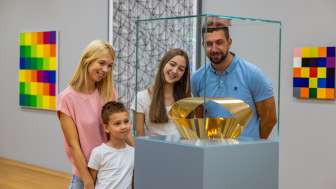 Familiebezoek aan het Kunstmuseum Liechtenstein Familie kijkt naar een gouden sculptuur in het Kunstmuseum Liechtenstein - kunst voor jong en oud in het hart van Vaduz.
