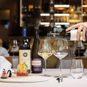 Een ober schenkt witte wijn in bij een elegant gerecht in restaurant Alpspitz.