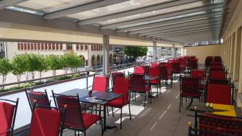 Zonnig terras met rode stoelen en witte tafels