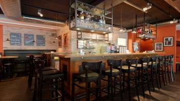 Stijlvolle interieurfoto van de bar in het New Castle Vaduz met een goed gevuld flessenrek en gezellige zithoek.