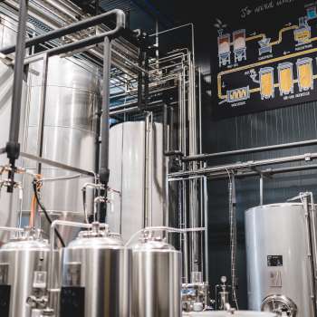 Zicht op de technische ruimte van de brouwerij met het complexe leidingsysteem en de moderne roestvrijstalen tanks.