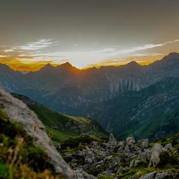 Zonsondergang op de bergkam - De zon zakt achter de bergtoppen en baadt het alpenpanorama in warme avondkleuren