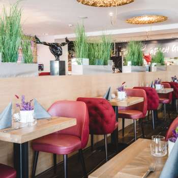 : Ruim gedekte tafels in het PUR Restaurant & Bar met rode stoelen en bloemendecoraties.