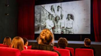 Bezoekers zitten in een rode bioscoopzaal in de oude bioscoop in Vaduz en kijken naar een historische film over Liechtenstein.