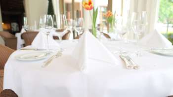 Feestelijk gedekte tafel met wit tafelkleed en verse tulp