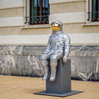 Zijaanzicht van een zilveren astronautensculptuur met een goudkleurig vizier op de Bad Ragartz tentoonstelling in Vaduz