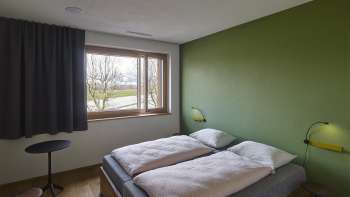 Tweepersoonskamer met groen geschilderde muur in jeugdherberg Schaan/Vaduz