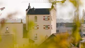 Close-up van de historische toren van het stadhuis van Vaduz met opvallende rode luiken, omringd door bouwkranen op de achtergrond.