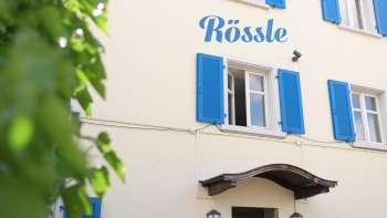 Buitenaanzicht van Restaurant Rössle met blauwe luiken en gezellige ingang.