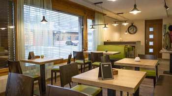 Moderne bistro met een gezellige sfeer, houten tafels en stijlvolle groene banken