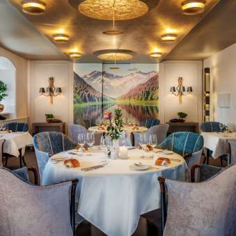 Ronde tafels met wijnglazen en kaarsen in de elegante eetzaal van het Park Hotel Sonnenhof in Vaduz, Liechtenstein