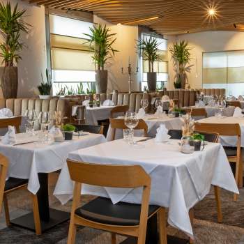 Uitzicht op het stijlvol ingerichte Alpspitz restaurant met witgeklede tafels en een moderne, lichte sfeer.