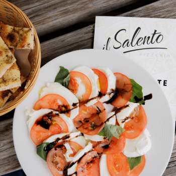 Verse pizza met tomatensaus en rucola, geserveerd op een rustieke houten tafel