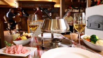 Close-up van kaasfondue met vers brood, groenten en wijn in een stijlvolle omgeving