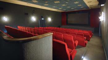 Zijaanzicht van de bioscoopzaal van het Altes Kino Vaduz met rode fauteuils en sfeervolle verlichting.