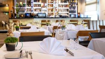  Smaakvol gedekte tafel in het Alpspitz restaurant met uitzicht op de bar op de achtergrond.