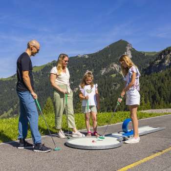  Gezin speelt samen minigolf in de bergen van Malbun in de stralende zon